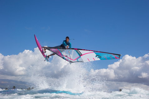 Planche de windsurf freestyle Fanatic Skate TE en saut aérien au-dessus des vagues en bleu et rose