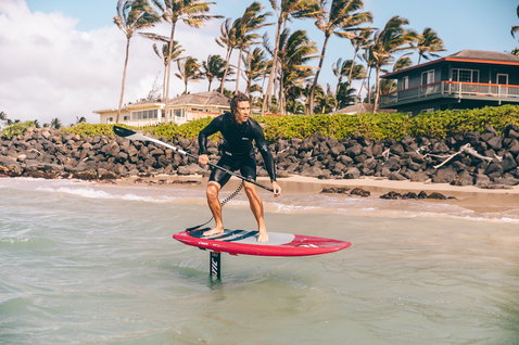 Fanatic Sky SUP foil board in red during foiling at a tropical beach shore