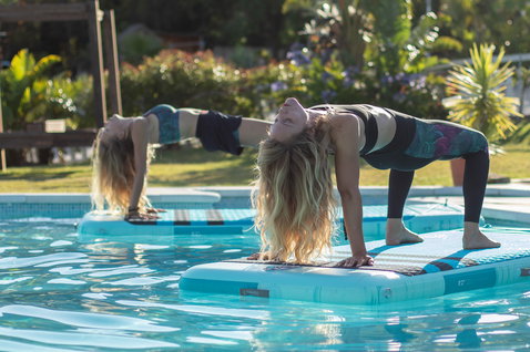 Duotone Air Mat tapis SUP gonflable 8'2" en turquoise lors d'une séance de yoga SUP en piscine
