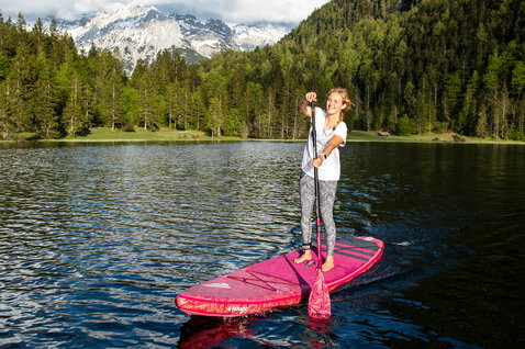 Duotone Diamond Air Touring inflatable SUP board 11'6" in pink during stand-up paddling on an alpine lake