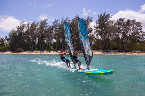 Duotone Tandem Air Premium inflatable SUP windsurf board 16"x34" in teal and yellow-green with two riders on the ocean