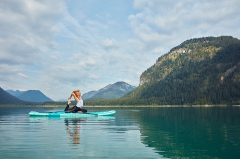 Duotone SUP Fly Air Fit inflatable SUP board during SUP yoga on a calm alpine lake