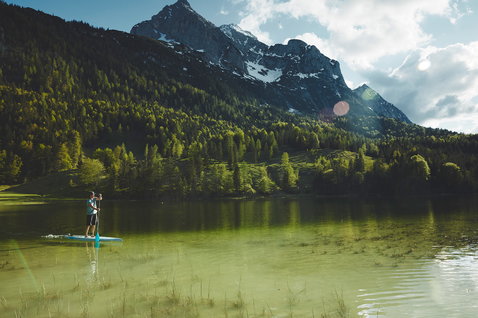 Duotone Ray Pure touring SUP board during paddling on an Alpine lake with mountain backdrop