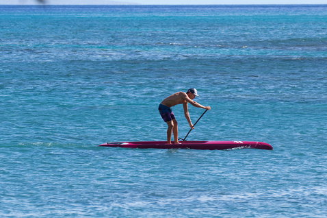 Planche de SUP de course Duotone Strike Carbon lors du paddle sur océan turquoise en rouge cramoisi