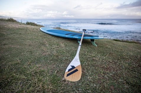 Duotone Bamboo Carbon 50 adjustable 3-piece SUP paddle in bamboo and white at the coast