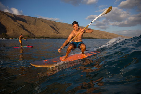 Duotone Bamboo Carbon 50 adjustable 3-piece SUP paddle in use during wave riding on the ocean at golden hour