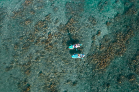 Duotone Fly Air aufblasbares SUP Board beim Paddeln über einem tropischen Korallenriff in türkisem Wasser