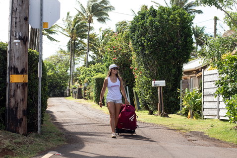 Fanatic Diamond Air inflatable SUP board bag on wheels in red being wheeled along a tropical street