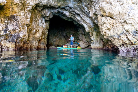 Duotone Ray Air Premium aufblasbares Touring SUP Board beim Paddeln in einer Meereshöhle im Mittelmeer