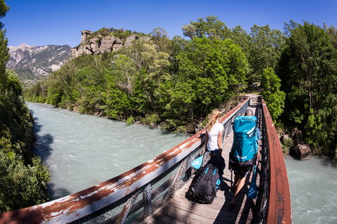 Fanatic Rapid Air Touring inflatable SUP backpack in teal during river touring in an alpine mountain landscape