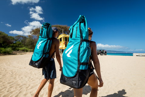 Fanatic Fly Air Pocket iSUP Rucksack in türkis und schwarz beim Tragen am Strand