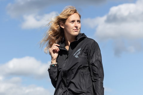 Fanatic windbreaker jacket women in black worn at the coast against a blue sky