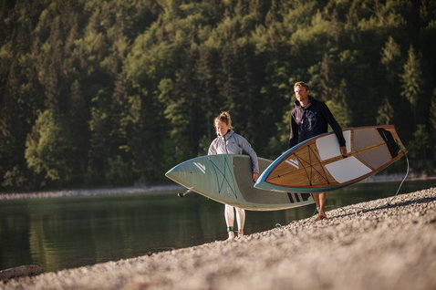 Fanatic Ray Bamboo Edition SUP board carried along a mountain lake shore at golden hour