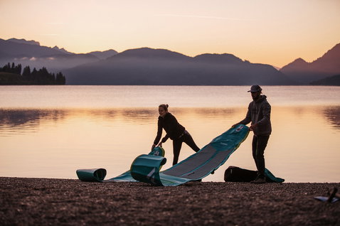 Fanatic Ray Air Pocket aufblasbares Touring-SUP 11'6" in türkis beim Aufrollen am Bergsee im Abendlicht