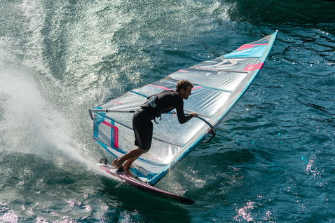 Fanatic Falcon Slalom TE race windsurf board during windsurfing on Lake Garda in teal and pink