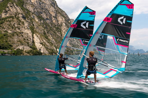 Fanatic Falcon Slalom TE race windsurf board during windsurfing on an alpine lake in cyan and pink