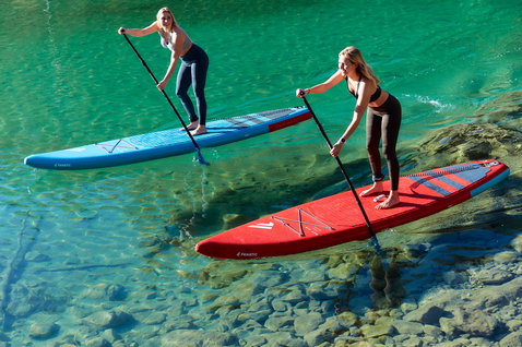 Fanatic Ray Air Pure aufblasbares Touring SUP Board beim Paddeln auf türkisfarbenem Bergsee in rot und blau