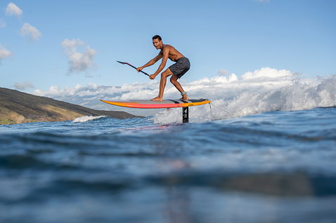 Fanatic Mast-Fuselage Set AL 3.0 lors du SUP foiling sur l'océan avec littoral en arrière-plan