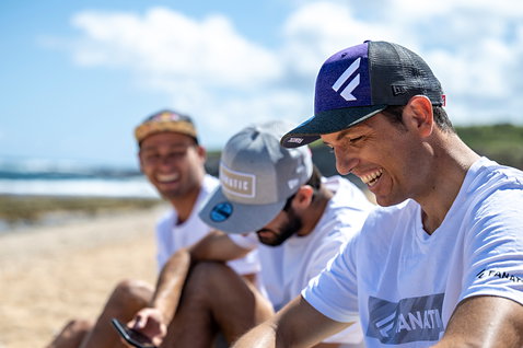 Fanatic Cap F trucker cap in purple and charcoal worn at the beach