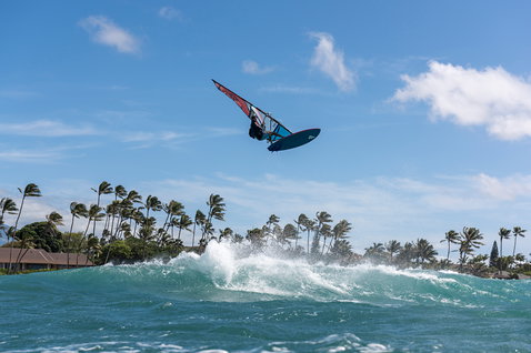 Fanatic Grip TE wave windsurf board during aerial manoeuvre over ocean waves at tropical beach