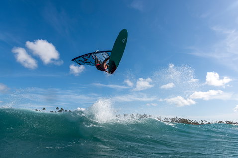 Fanatic FreeWave Windsurf-Wellenboard beim Wave-Reiten mit Aerial-Manöver über einer tropischen Welle