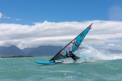 Fanatic FreeWave TE wave windsurf board during wave riding on the ocean with mountain backdrop