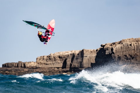 Fanatic Grip XS wave windsurf board during wave riding at a rocky coastal cliff