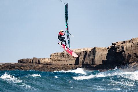 Fanatic Grip XS wave windsurf board during wave riding at a rocky coastline