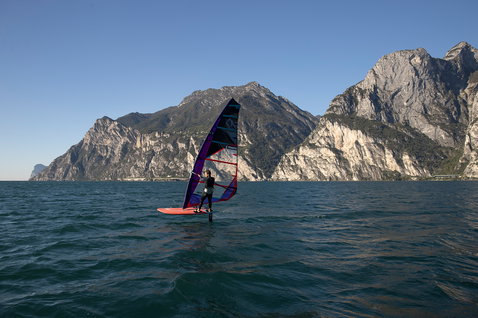 Fanatic Falcon Lightwind windsurf board during windsurfing on a mountain lake with dramatic rocky cliffs