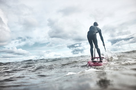 Duotone Blitz Carbon SUP Race Board beim Paddeln im offenen Ozean unter bewölktem Himmel