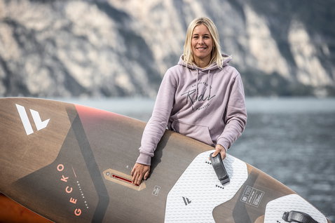 Fanatic Gecko Eco freeride windsurf board in dark brown and copper at a mountain lake