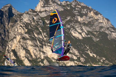 Fanatic Gecko Foil LTD 135L windsurf foil board during foiling on an alpine lake with rocky mountains