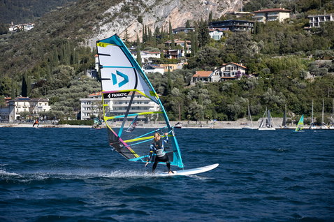 Fanatic Gecko HRS freeride windsurf board during windsurfing on a lake with mountain backdrop