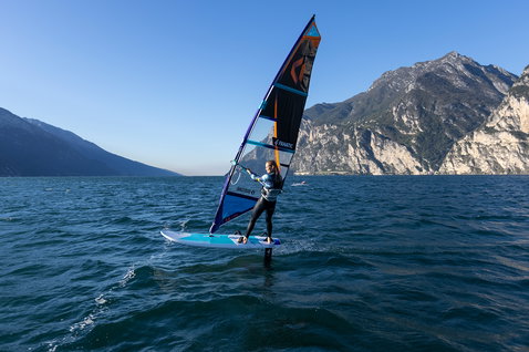 Fanatic Stingray HRS windsurf foil board during foiling on an alpine lake in cyan and blue