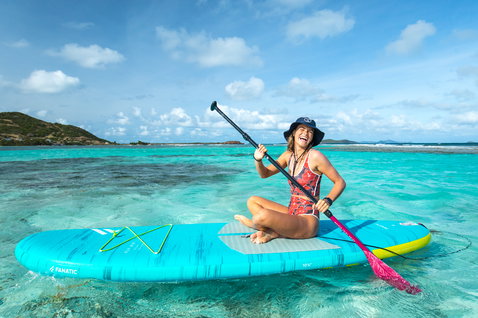 Fanatic Fly Air Pocket aufblasbares SUP Board 10'4" in türkis und gelbgrün beim Stand Up Paddling in tropischer Lagune