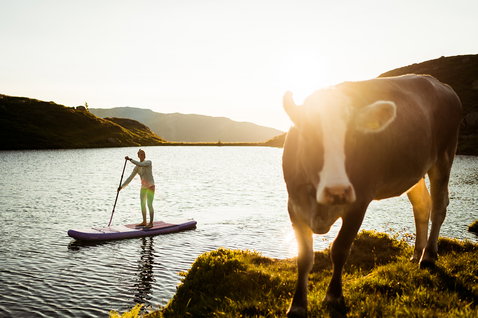 Duotone Diamond Air Pocket inflatable SUP board 10'4" during stand-up paddling on an alpine mountain lake at golden hour