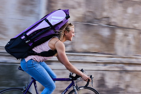 Fanatic Diamond Air Pocket SUP board bag in purple carried as backpack while cycling in the city