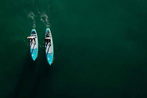 Duotone Ray Air Premium aufblasbares Touring SUP Board beim Stand-Up-Paddeln auf ruhigem grünem Wasser