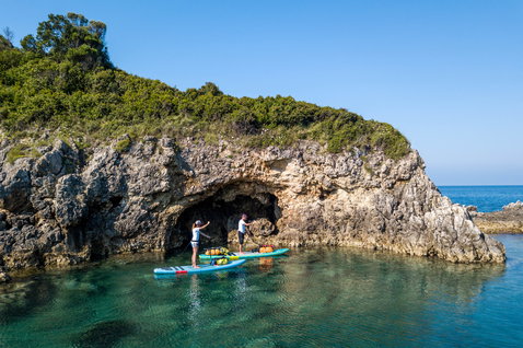 Duotone Ray Air Premium aufblasbares Touring SUP beim Paddeln an einer Felsenküste mit Meereshöhle