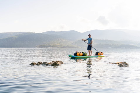 Duotone Ray Air Premium aufblasbares Touring SUP beim Paddeln auf einem ruhigen See mit Gepäck an Bord