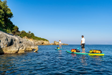 Duotone Ray Air Premium aufblasbares Touring SUP Board beim Küstentour-Paddeln an einer mediterranen Felsenbucht