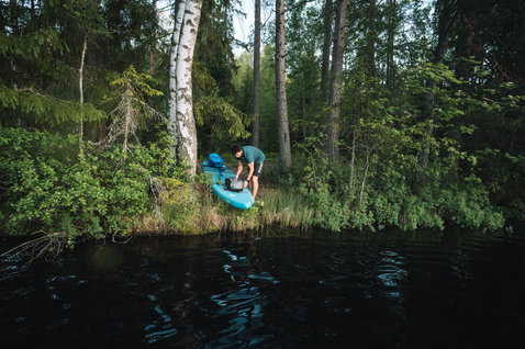 Duotone SUP Ray Air inflatable touring SUP board during paddling adventure at a forest lake in Finland