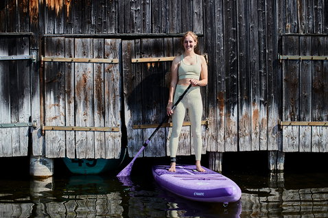 Duotone SUP Diamond Air Touring Pocket inflatable touring SUP board in purple during stand-up paddling at a boathouse