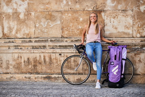Fanatic Diamond Air Touring Pocket SUP bag in purple with woman and bicycle against stone wall