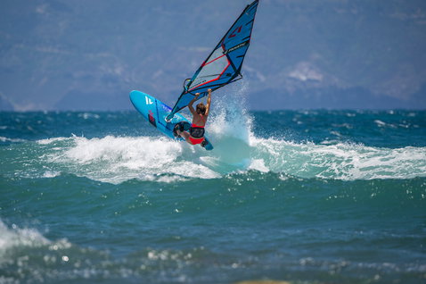 Fanatic FreeWave windsurf board during wave riding on the ocean in vivid blue