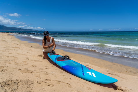 Fanatic FreeWave windsurf board in sky blue with magenta accents on a sunny Maui beach