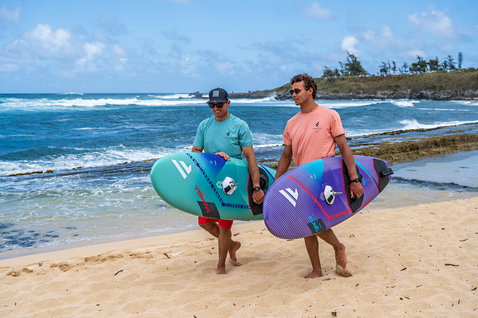 Planche de windsurf de vague Fanatic Grip TE portée sur une plage tropicale en bleu-vert