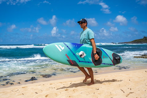 Fanatic Mamba TE Wave-Windsurfboard beim Tragen am Strand von Maui in mint und ozeanblau