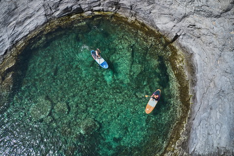 Duotone SUP Fly paddleboard lors du SUP dans une crique rocheuse aux eaux turquoise