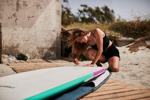 Planche SUP Duotone Stylemaster Bamboo lors d'une session de SUP vagues sur la plage de Sardaigne en blanc et turquoise